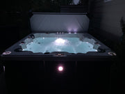 Hot tub with lights on at night in a dark outdoor setting