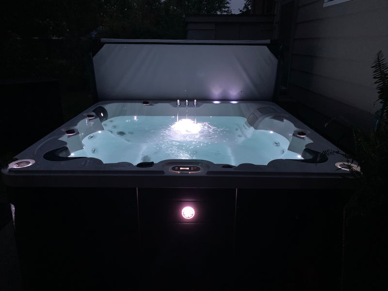 Hot tub with lights on at night in a dark outdoor setting